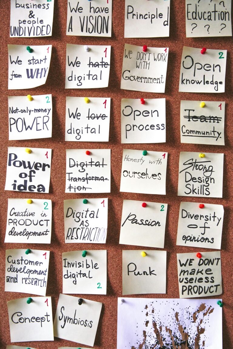 A corkboard filled with handwritten sticky notes featuring various business and digital transformation concepts, including "We have a vision," "Open knowledge," "Power of idea," and "Diversity of opinions." The notes reflect a creative brainstorming session focused on values, principles, and innovative practices in a collaborative environment.